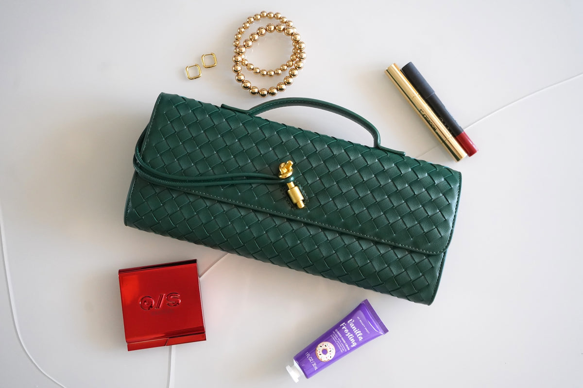 a leather dark green clutch bag with a gold closing in the middle